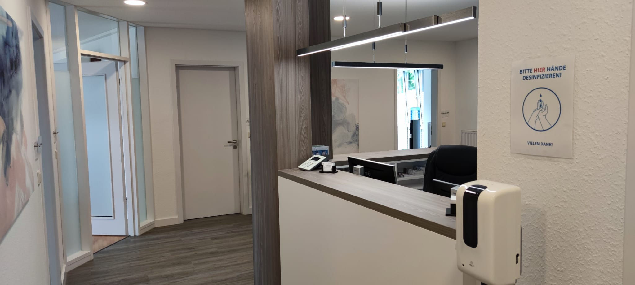 Der Empfang unserer Praxis mit heller Theke und Holzdetails